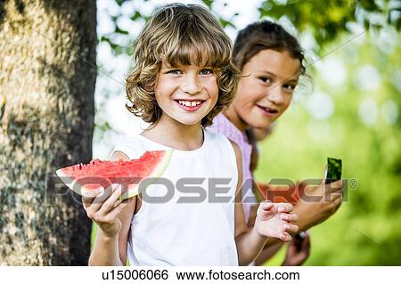 Stock Photograph - Children eating watermelon in park.. Fotosearch