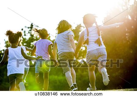 Stock Photograph - Children holding hands and running in park.. Fotosearch