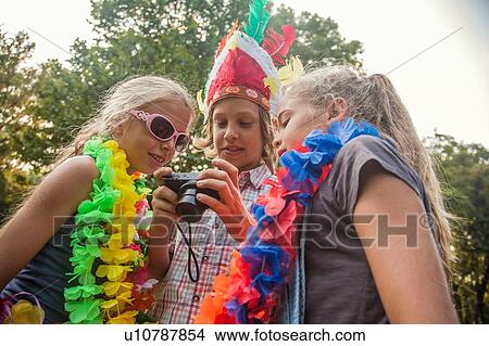 Picture - Children in costume looking at photographs in camera. Fotosearch