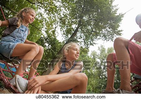 Stock Image - Children talking on net swing. Fotosearch