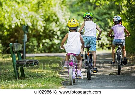 Children wearing helmeta and cycling in park. View Large Photo Image Stock Photo - Children wearing helmeta and cycling in park.. Fotosearch