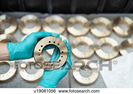 Stock Photograph - Close up of engineer inspecting bronze parts in gearbox factory. Fotosearch