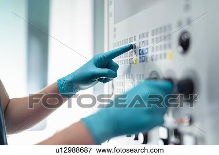 Stock Photo - Close up of hands of ap0entice engineer at controls of CNC machine in gearbox factory. Fotosearch