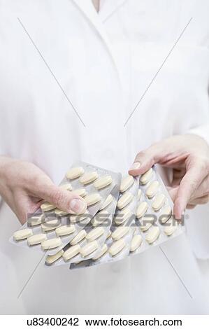 Close-up of pharmacist holding pills in blister packs. View Large Photo Image Stock Image - Close-up of pharmacist holding pills in blister packs.. Fotosearch