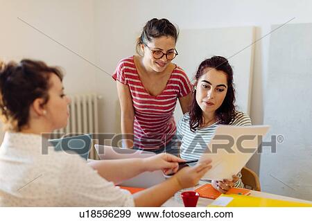 Stock Photo - Colleagues discussing documents. Fotosearch