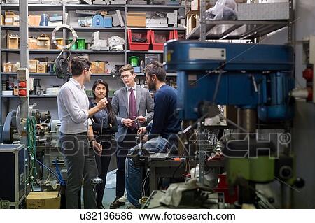 Stock Photograph - Colleagues in discussion in fencing prop workshop. Fotosearch