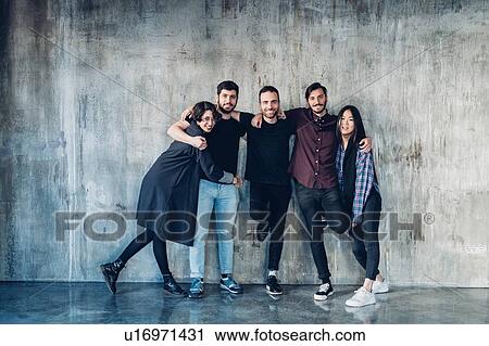 Colleagues posing for group photo against concrete wall View Large Photo Image Stock Image - Colleagues posing for group photo against concrete wall. Fotosearch