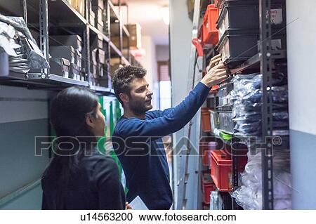 Stock Image - Colleagues working on delivery and packaging in warehouse. Fotosearch