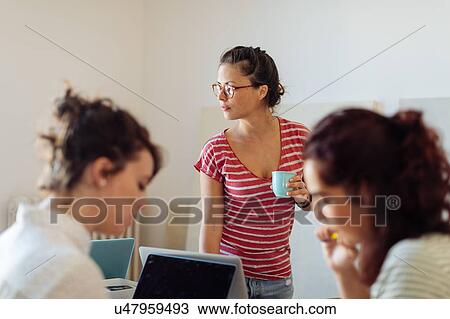 Stock Image - Colleagues working on project around table. Fotosearch