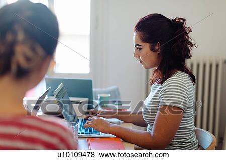 Stock Photo - Colleagues working on project around table. Fotosearch