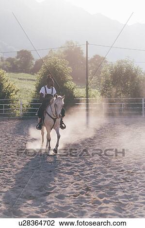 Stock Image - Cool young man horse riding in rural equestrian arena, Primaluna, Trentino-Alto Adige, Italy. Fotosearch