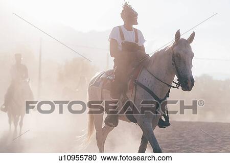 Cool young man riding horse in dusty rural equestrian arena View Large Photo Image Stock Image - Cool young man riding horse in dusty rural equestrian arena. Fotosearch