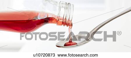 Stock Image - Cough syrup pouring onto a spoon.. Fotosearch