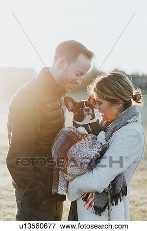 Stock Photo - Couple carrying their puppy in woollen blanket. Fotosearch