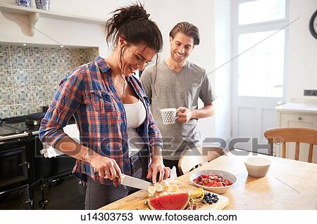 Couple chatting while slicing fresh fruit at kitchen table View Large Photo Image Stock Image - Couple chatting while slicing fresh fruit at kitchen table. Fotosearch