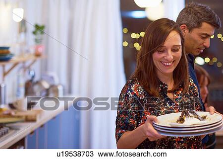 Stock Image - Couple cleaning up at dinner party. Fotosearch