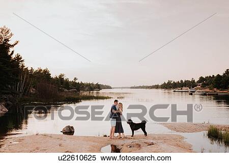 Stock Photography - Couple enjoying view of river with pet dog, Algonquin Park, Canada. Fotosearch