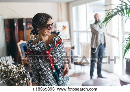 Stock Image - Couple getting ready to leave house. Fotosearch