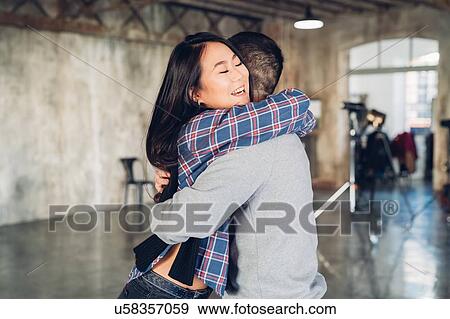 Stock Photo - Couple hugging in open plan studio. Fotosearch
