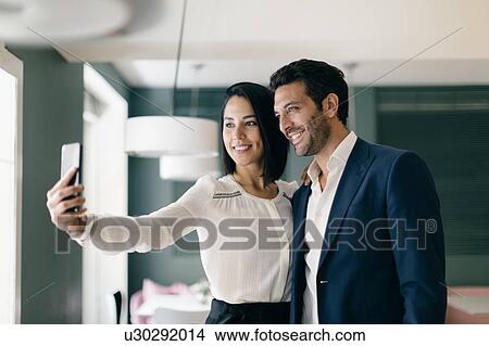 Picture - Couple in hotel taking smartphone selfie. Fotosearch