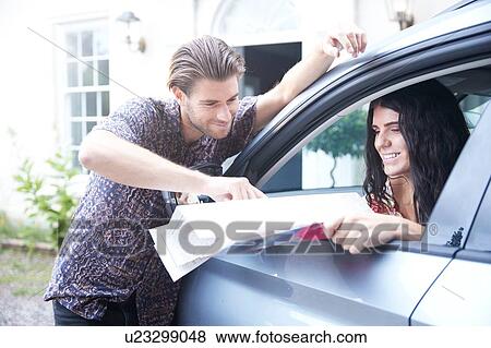 Couple in parked car outside front door looking at folding map View Large Photo Image Stock Photo - Couple in parked car outside front door looking at folding map. Fotosearch