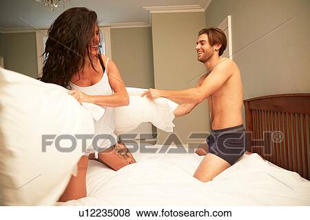 Couple in underwear having a pillow fight on bed View Large Photo Image Stock Photo - Couple in underwear having a pillow fight on bed. Fotosearch