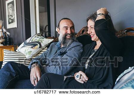 Couple laughing on sofa View Large Photo Image Stock Photo - Couple laughing on sofa. Fotosearch