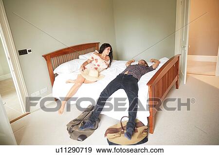 Stock Photo - Couple lying on hotel bed. Fotosearch
