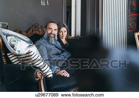 Couple on sofa looking at camera View Large Photo Image Stock Photo - Couple on sofa looking at camera. Fotosearch