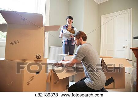 Stock Photo - Couple packing belongings in cardboard boxes. Fotosearch