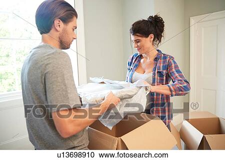 Stock Image - Couple packing belongings into cardboard box. Fotosearch