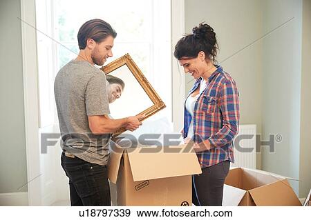 Stock Photo - Couple packing mirror into cardboard box. Fotosearch