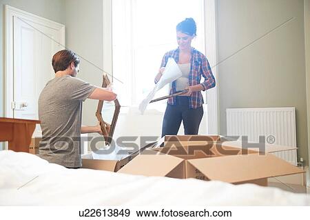 Stock Photo - Couple packing mirror into cardboard box. Fotosearch
