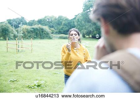 Couple playing with soap bubbles in field View Large Photo Image Stock Image - Couple playing with soap bubbles in field. Fotosearch