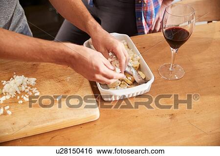 Couple putting vegetables in roasting dish at kitchen table, close up of hands View Large Photo Image Stock Photograph - Couple putting vegetables in roasting dish at kitchen table, close up of hands. Fotosearch