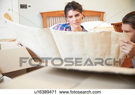 Stock Image - Couple reading blueprint layout in new home. Fotosearch