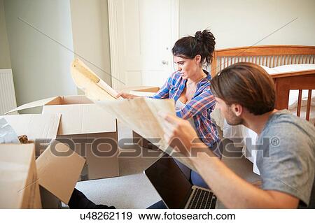 Stock Photo - Couple reading blueprint layout in new home. Fotosearch