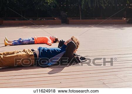 Couple relaxing on wooden decking View Large Photo Image Stock Photo - Couple relaxing on wooden decking. Fotosearch