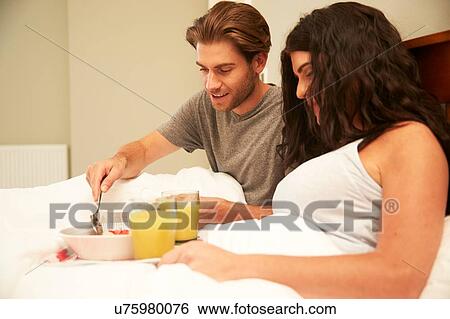 Couple sharing fruit and orange juice breakfast in bed View Large Photo Image Stock Photograph - Couple sharing fruit and orange juice breakfast in bed. Fotosearch