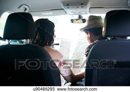 Stock Image - Couple sitting in car looking at folding map, rear view. Fotosearch