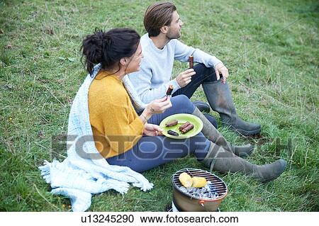 Couple sitting in rural field having barbecue View Large Photo Image Stock Image - Couple sitting in rural field having barbecue. Fotosearch
