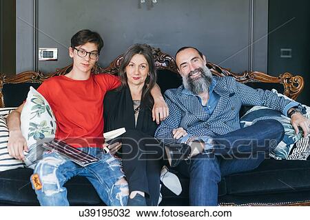 Stock Image - Couple sitting on antique sofa with son. Fotosearch