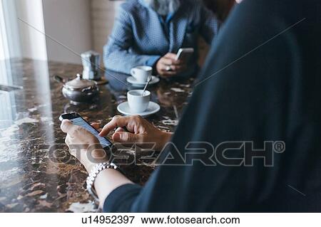 Couple using cellphone over coffee in kitchen View Large Photo Image Stock Photo - Couple using cellphone over coffee in kitchen. Fotosearch