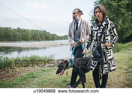Stock Photo - Couple walking dog by lake. Fotosearch