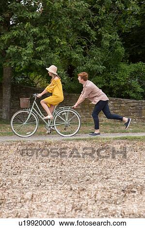 Stock Image - Couple with pushbike in countryside. Fotosearch