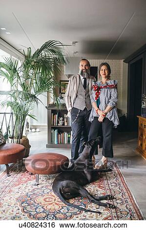 Stock Photograph - Couple with their dog in living room at home. Fotosearch