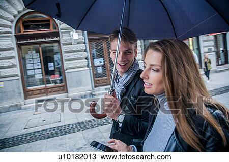 Stock Image - Couple with umbrella on morning commute, Budapest, Hungary. Fotosearch