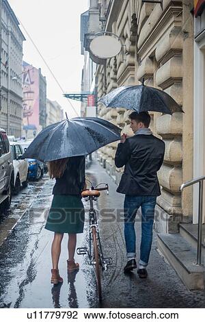 Stock Image - Couple with umbrella on morning commute, Budapest, Hungary. Fotosearch