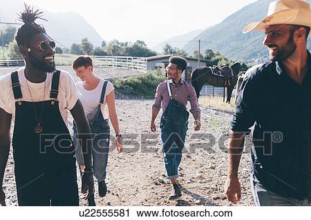 Stock Image - Cowboy with young adult friends in equestrian arena, Primaluna, Trentino-Alto Adige, Italy. Fotosearch