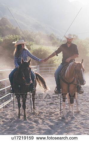 Cowgirl and boyfriend holding hands while on horseback in equestrian arena, Primaluna, Trentino-Alto Adige, Italy View Large Photo Image Stock Photo - Cowgirl and boyfriend holding hands while on horseback in equestrian arena, Primaluna, Trentino-Alto Adige, Italy. Fotosearch